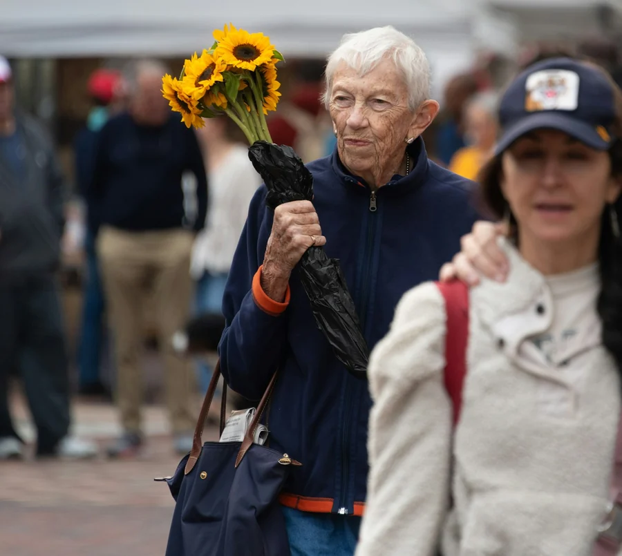 Older woman carrying sunflowers through a Florida community market